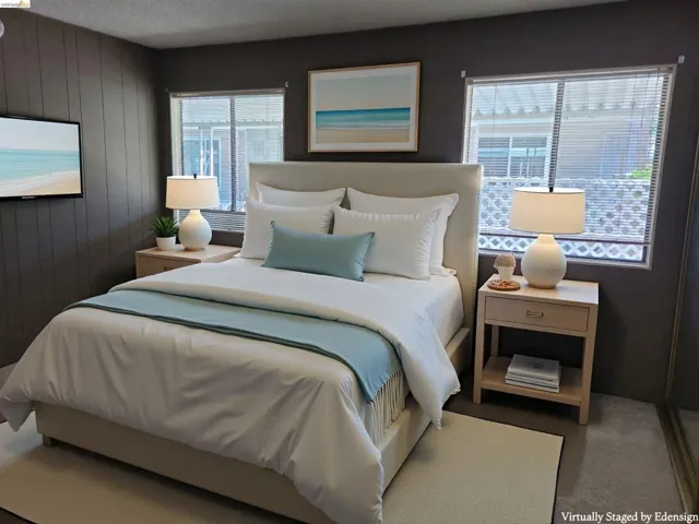 Primary bedroom with mirrored closet doors, staged with furniture.