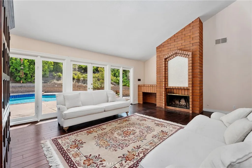 Sunken living room with firepalce, vaulted ceilings, crown molding, floor to ceiling windows that open and French doors leading to the back yard pool.