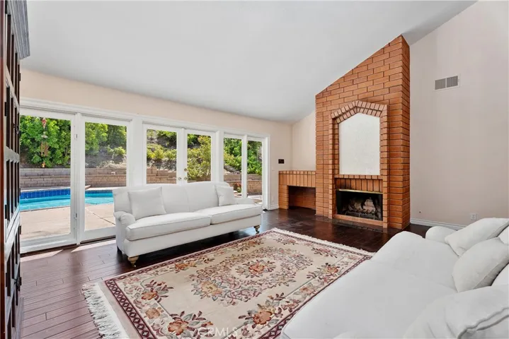 Sunken living room with firepalce, vaulted ceilings, crown molding, floor to ceiling windows that open and French doors leading to the back yard pool.