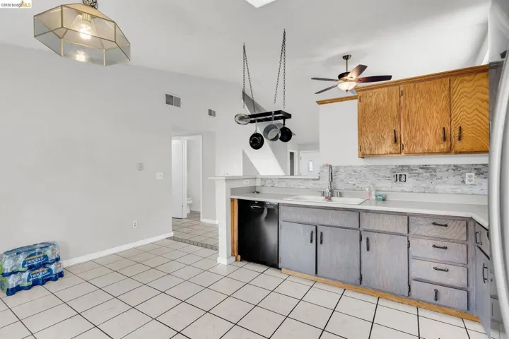 Kitchen with light countertops, black dishwasher, lofted ceiling, a ceiling fan, and light tile patterned floors