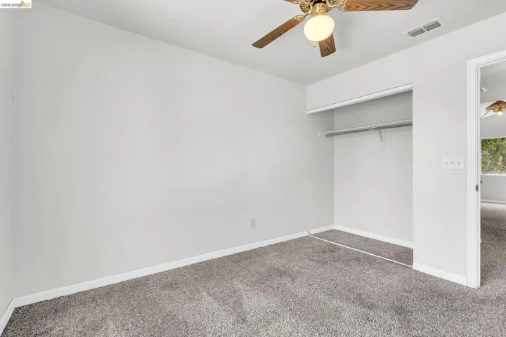 Unfurnished bedroom with carpet floors, a closet, and a ceiling fan