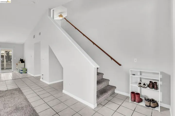 Stairway with tile patterned flooring and a high ceiling