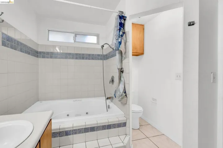 Full bath featuring vanity, a combined bath / shower with jetted tub, and light tile patterned floors