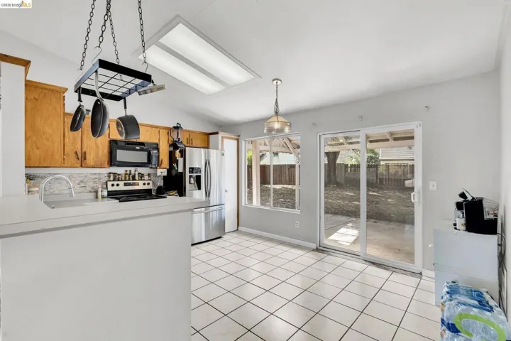Kitchen featuring light countertops, vaulted ceiling, stainless steel appliances, light tile patterned flooring, and tasteful backsplash