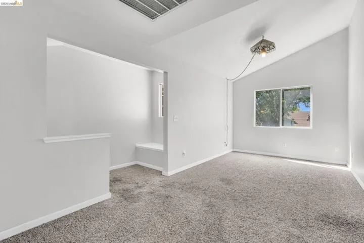 Unfurnished room with carpet flooring and vaulted ceiling