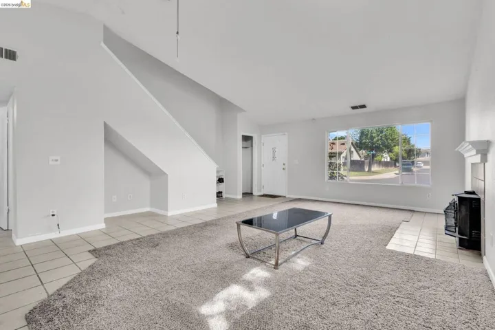 Unfurnished living room featuring light tile patterned floors, a wood stove, and lofted ceiling