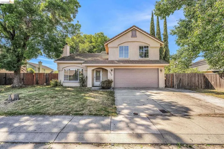 Traditional-style home with stucco siding, a garage, concrete driveway, a chimney, and a tiled roof
