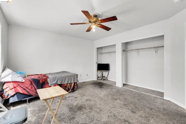 Carpeted bedroom featuring multiple closets and ceiling fan