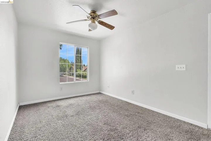 Carpeted empty room with ceiling fan and baseboards