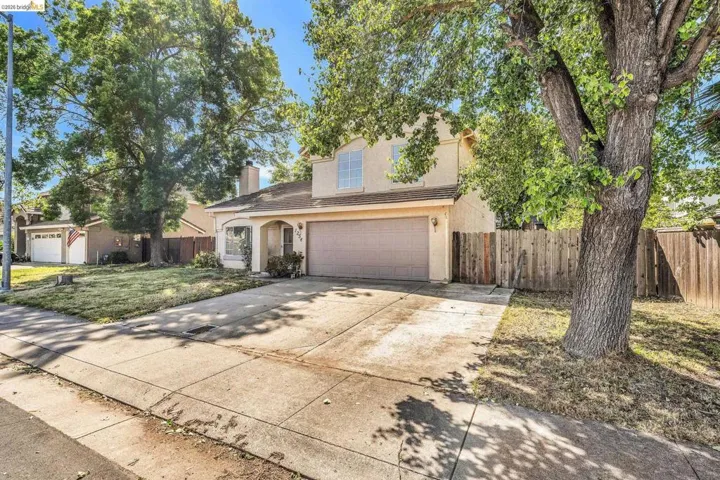 Traditional-style home with a garage, stucco siding, driveway, and a chimney