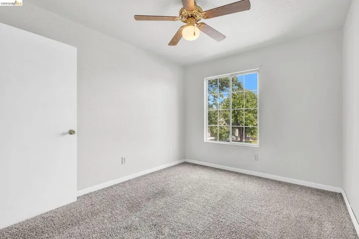Unfurnished room featuring a ceiling fan and carpet floors