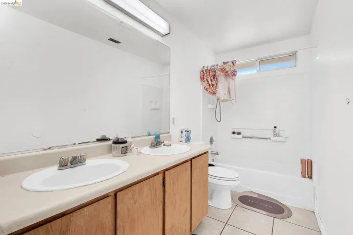 Bathroom featuring double vanity, shower / bath combination, and light tile patterned floors