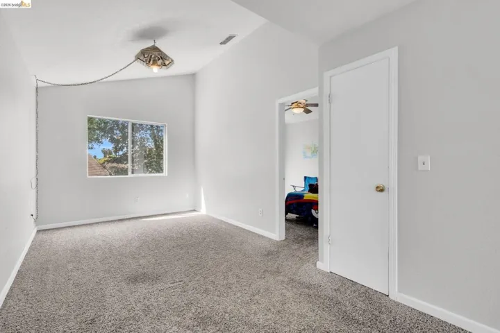 Unfurnished room featuring carpet flooring, lofted ceiling, and a ceiling fan