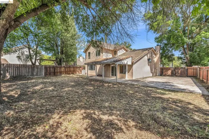 Back of house featuring a patio, a fenced backyard, a chimney, and stucco siding