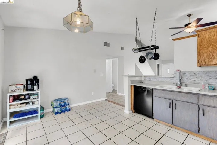 Kitchen with light countertops, dishwasher, lofted ceiling, ceiling fan, and light tile patterned floors