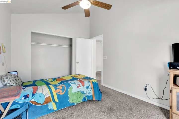 Carpeted bedroom featuring ceiling fan, a closet, and lofted ceiling