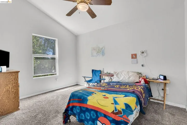 Bedroom featuring vaulted ceiling, carpet floors, and a ceiling fan