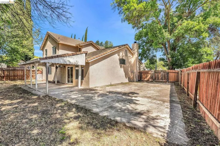 Back of property with stucco siding, a fenced backyard, a patio area, a chimney, and a tile roof