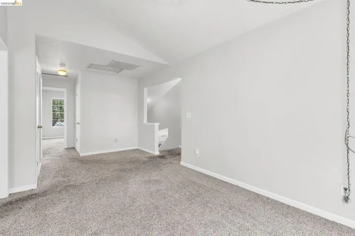 Spare room featuring vaulted ceiling and light colored carpet