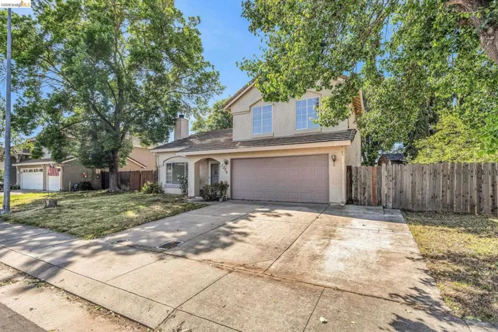 Traditional-style home featuring stucco siding, driveway, an attached garage, and a chimney