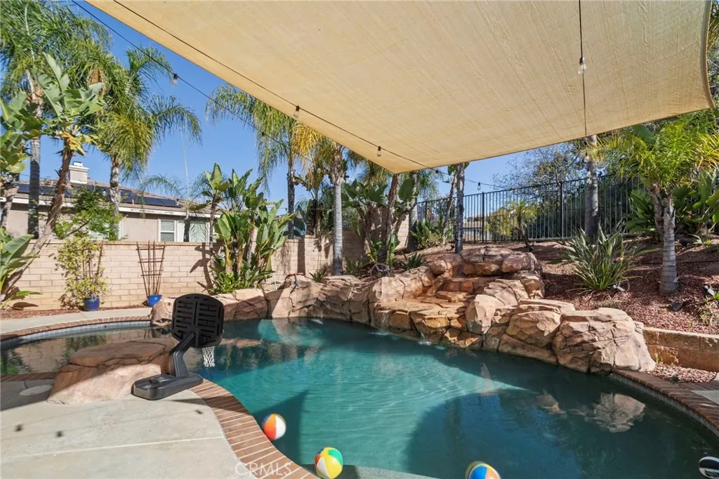 Pool with rock waterfall feature and surrounding landscaping