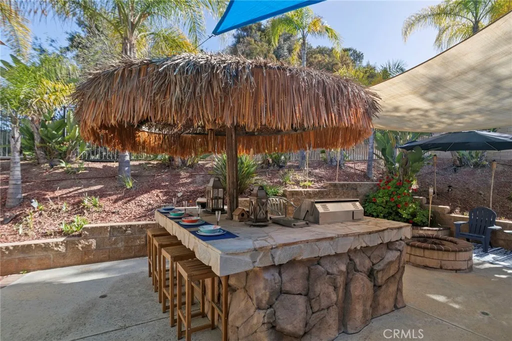 Outdoor entertaining area with covered seating, built-in bar, BBQ, and fire pit