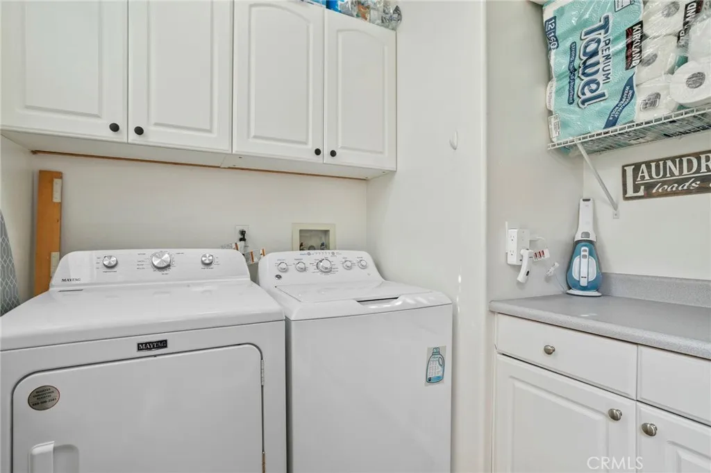 Convenient laundry room with upper cabinets and counter space for added storage