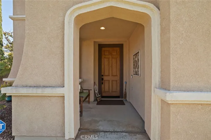 Covered front entry with an arched stucco detail and a solid wood door, creating a warm and welcoming first impression
