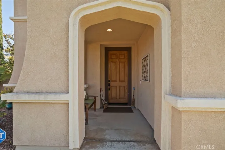 Covered front entry with an arched stucco detail and a solid wood door, creating a warm and welcoming first impression