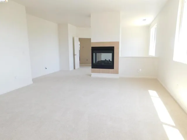 Unfurnished living room with light carpet and a fireplace