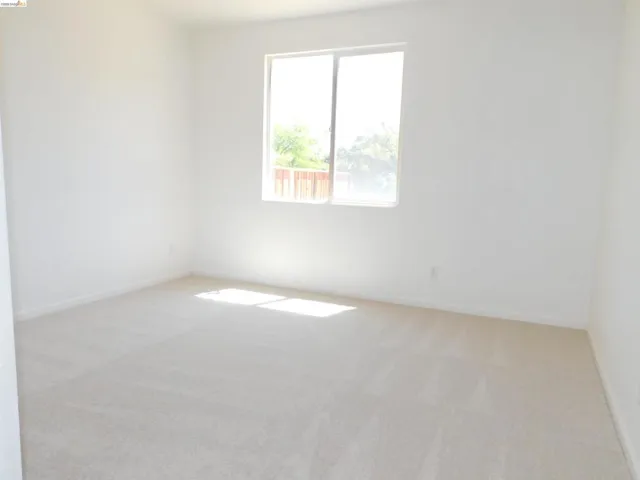 Empty room with light colored carpet and baseboards