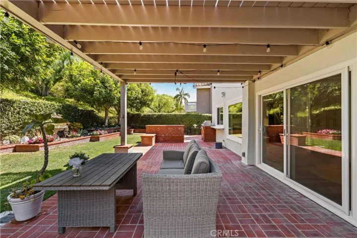 Covered patio view featuring outdoor seating, brick flooring, and seamless access to the backyard.