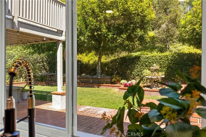 View from the kitchen window overlooking the backyard, offering greenery and natural light.