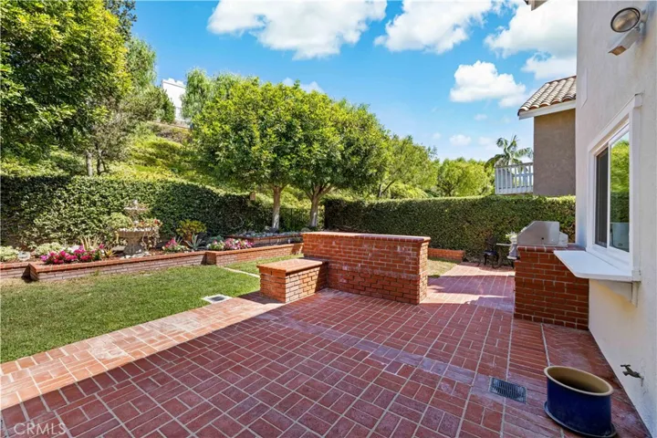 Backyard patio area featuring brick accents, open space, and a well-maintained lawn.