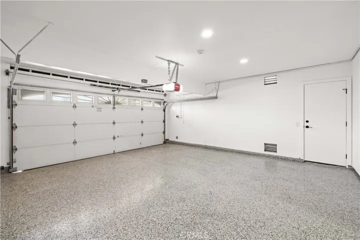 This spacious garage features a clean epoxy-style floor, ample room for parking and storage, and convenient access to the home.