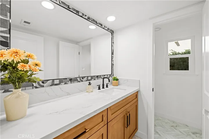 This bathroom showcases a clean and modern design with a sleek vanity, large mirror, and bright finishes, creating a fresh and inviting space.