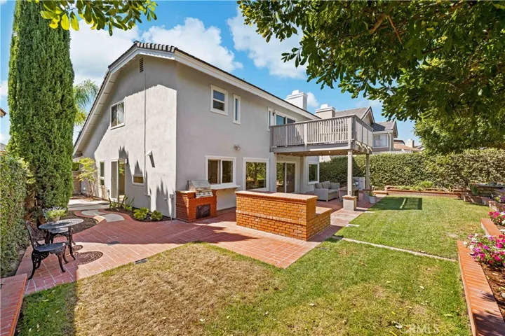 Wide backyard shot highlighting the spacious layout, outdoor features, and second-level balcony.