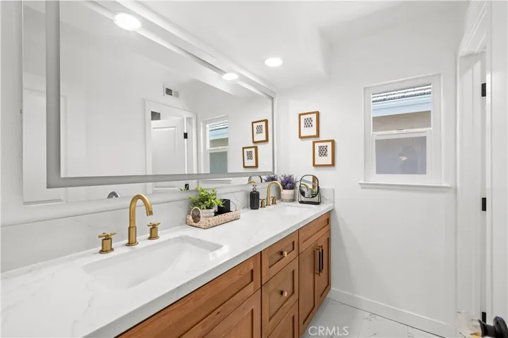 Main level bathroom with dual sinks, updated fixtures, and a bright, simple design.
