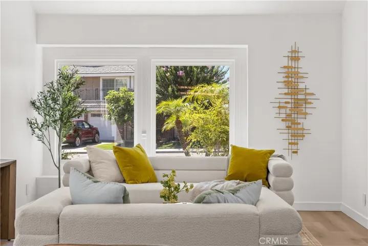 Living room seating area with large windows, offering natural light and front yard views.