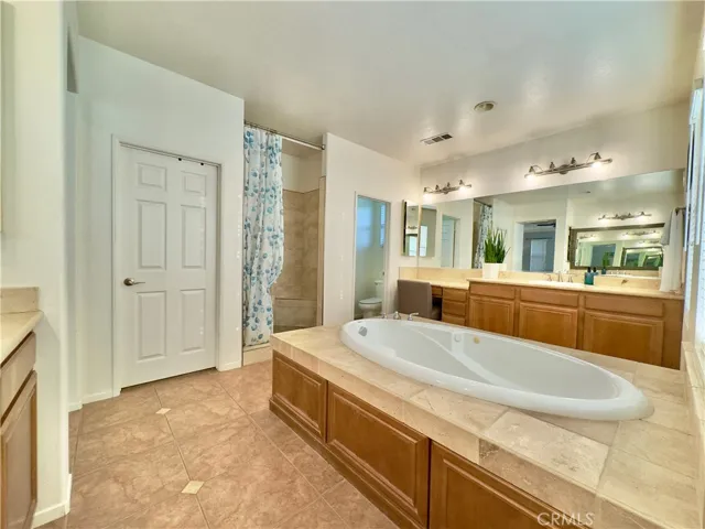 Grand Primary Bedroom Suite Bathroom with large soaking tub, separate vanities, water closet, and large walk-in closet and shower.