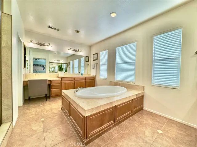 Grand Primary Bedroom Suite Bathroom with large soaking tub, separate vanities, water closet, and large walk-in closet and shower.