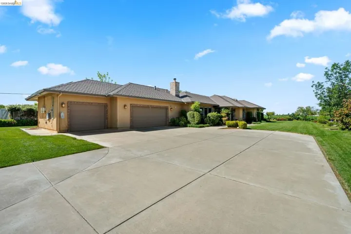 Prairie-style house featuring a front lawn, a garage, stucco siding, driveway, and a chimney