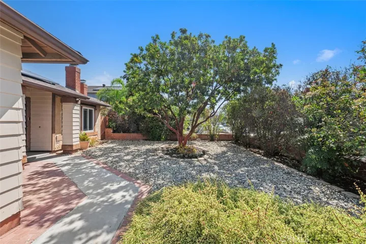 Front walkway is framed by mature landscaping and natural shade, creating a peaceful path to the entry. This outdoor space feels private and welcoming.