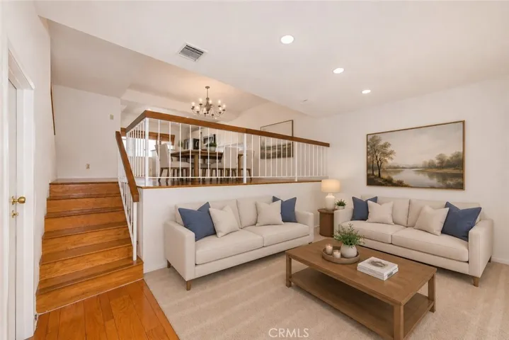 Virtually Staged Digitally altered photo of the living room with stairs to dining area