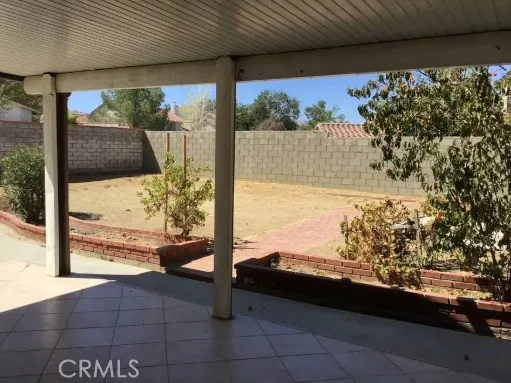 Partially tiled back yard features covered patio and hardscape