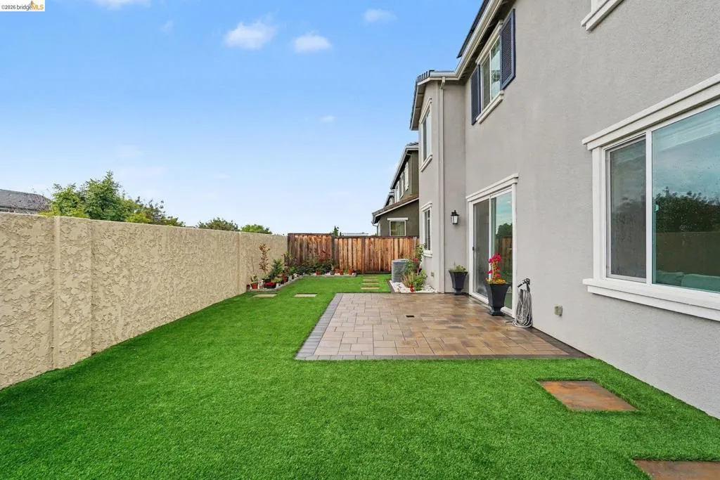 Expansive backyard featuring a paver patio and artificial turf