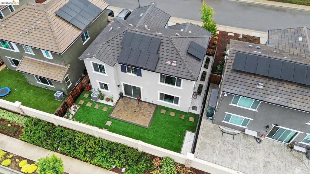 Rear exterior featuring a paver patio, artificial turf lawn, and a perimeter wall