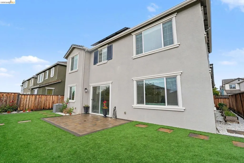 Expansive backyard featuring a manicured lawn, a paved patio, and a privacy fence