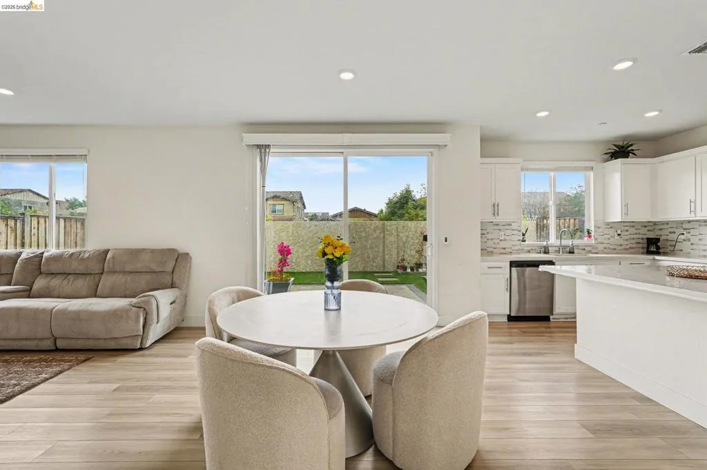 Open-concept interior featuring light wood-finish flooring, recessed lighting, and a sliding glass door to the backyard