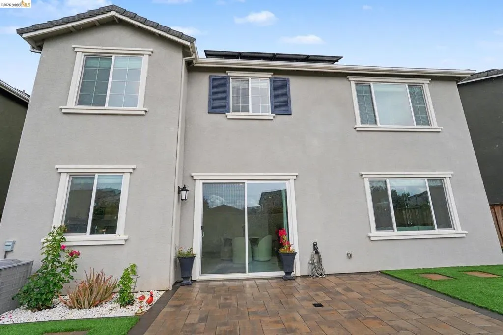 Rear exterior featuring a paver patio with artificial turf accents